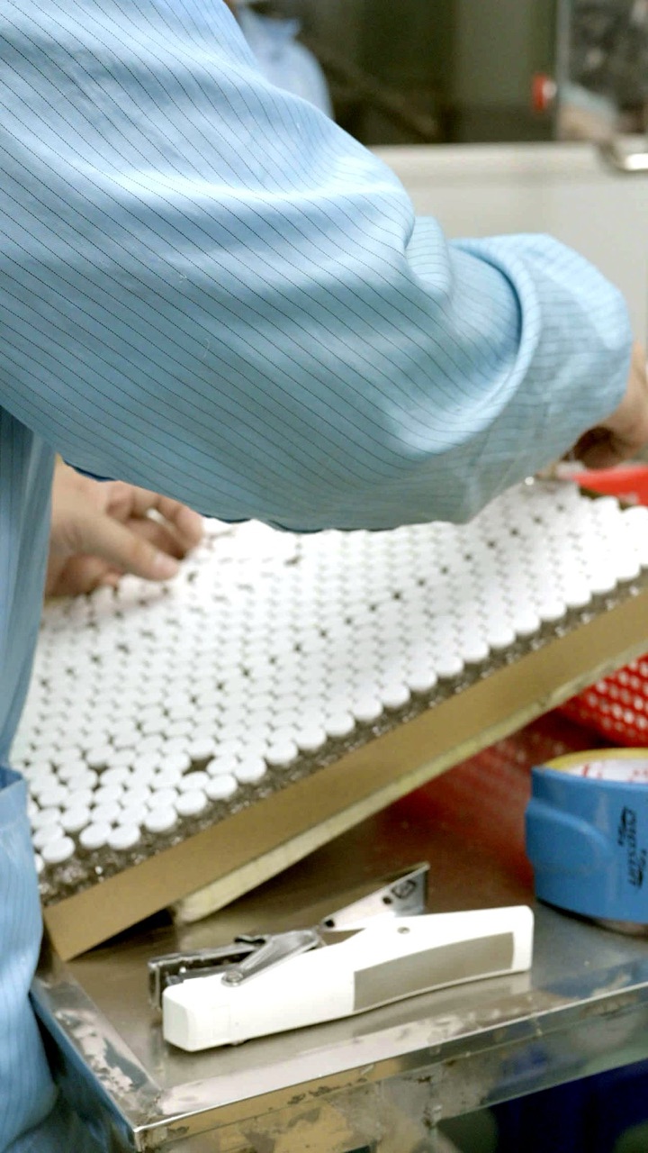 Operator transferring a tray of vials at the packing bench